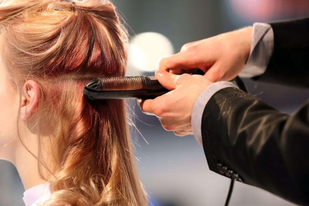 Woman having hair curled by professional