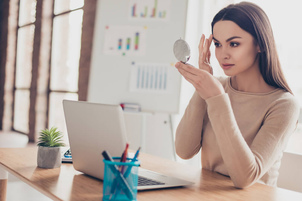 Woman looking at eyebrows in mirror