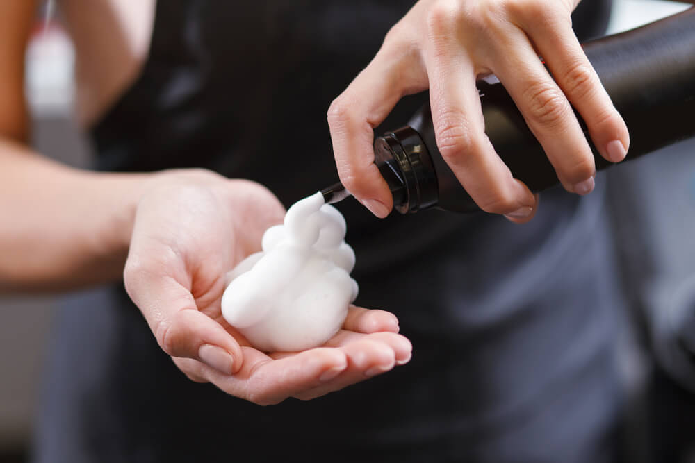 Woman applying hair mousse to hand