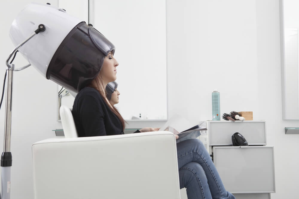 Woman with hair mask under hooded dryer