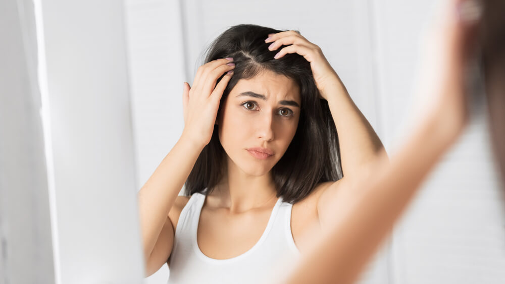 Woman looking at hair in mirror