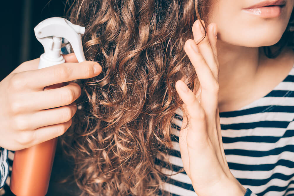 Woman spraying hair - curly hair product